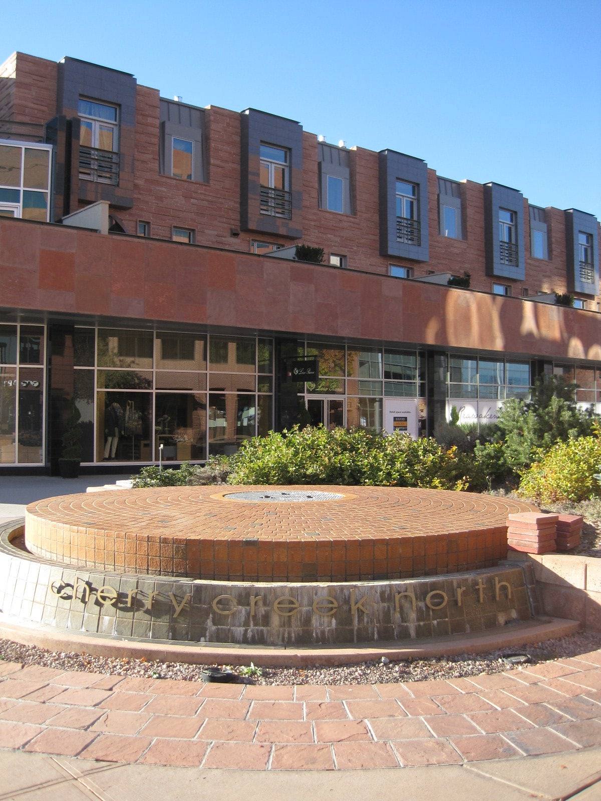 Shopfronts and brick residences above the Cherry Creek North fountain plaza