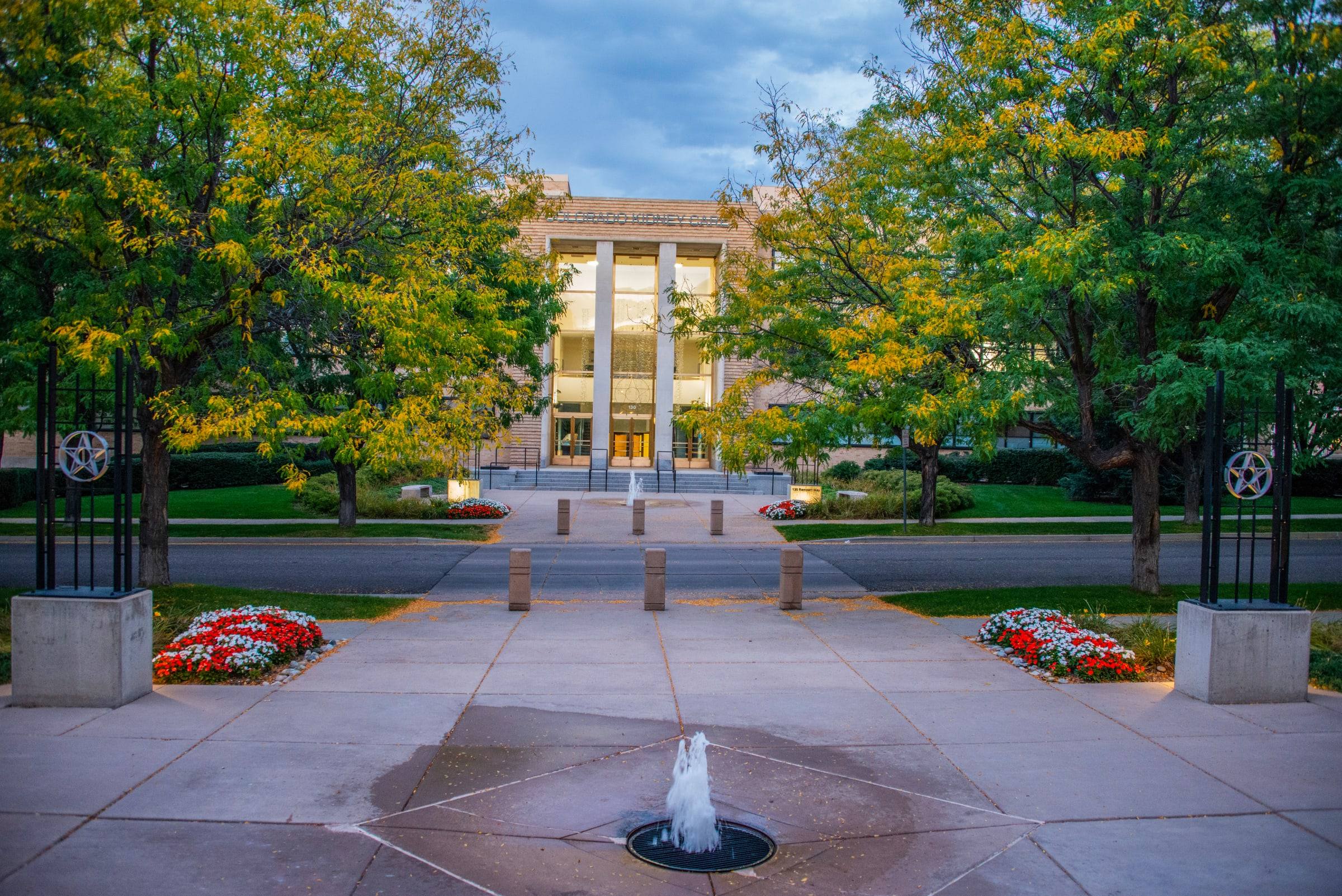 Historic Photography and Armament School buildings at Lowry, framed by trees and a fountain